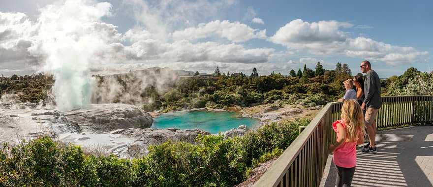 Family viewing the geothermal lake and geyser at Te Puia in Rotorua, New Zealand