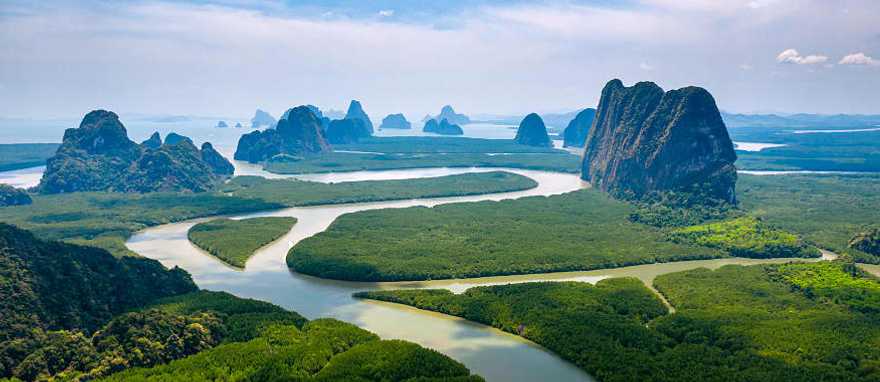 Aerial view of towering limestone cliffs and mangrove forest in Phang Nga Bay, Thailand.