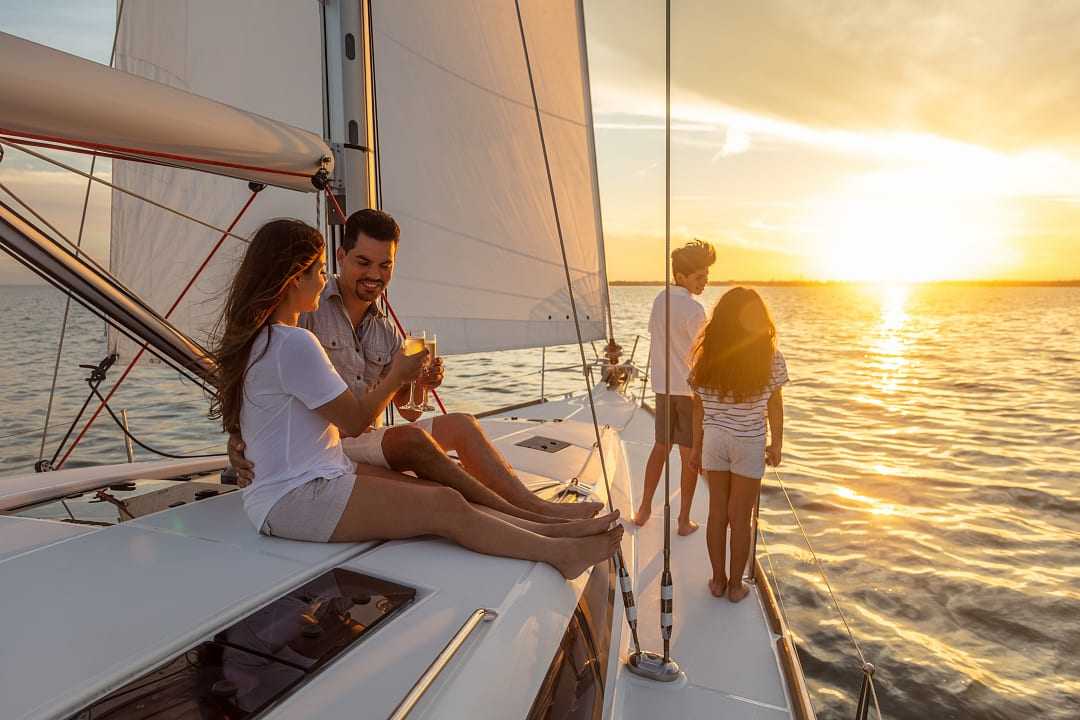 Young Hispanic brother and sister watching the sunset from luxury yacht with parents relaxing on deck enjoying togetherness