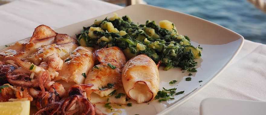 Fried squid with boiled potatoes and Swiss chard. Traditional Croatian cuisine, Rovinj