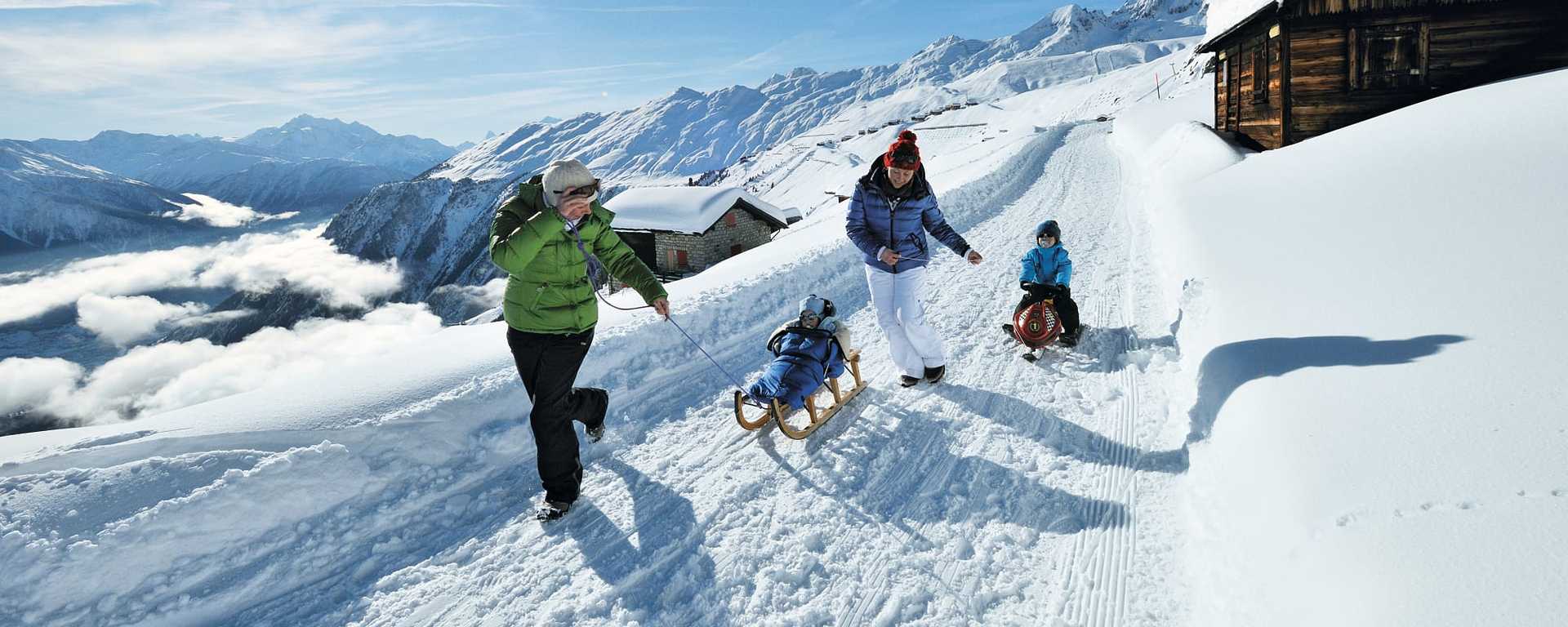 Family sledding on the Aletschbord at Belalp in Canton Valais