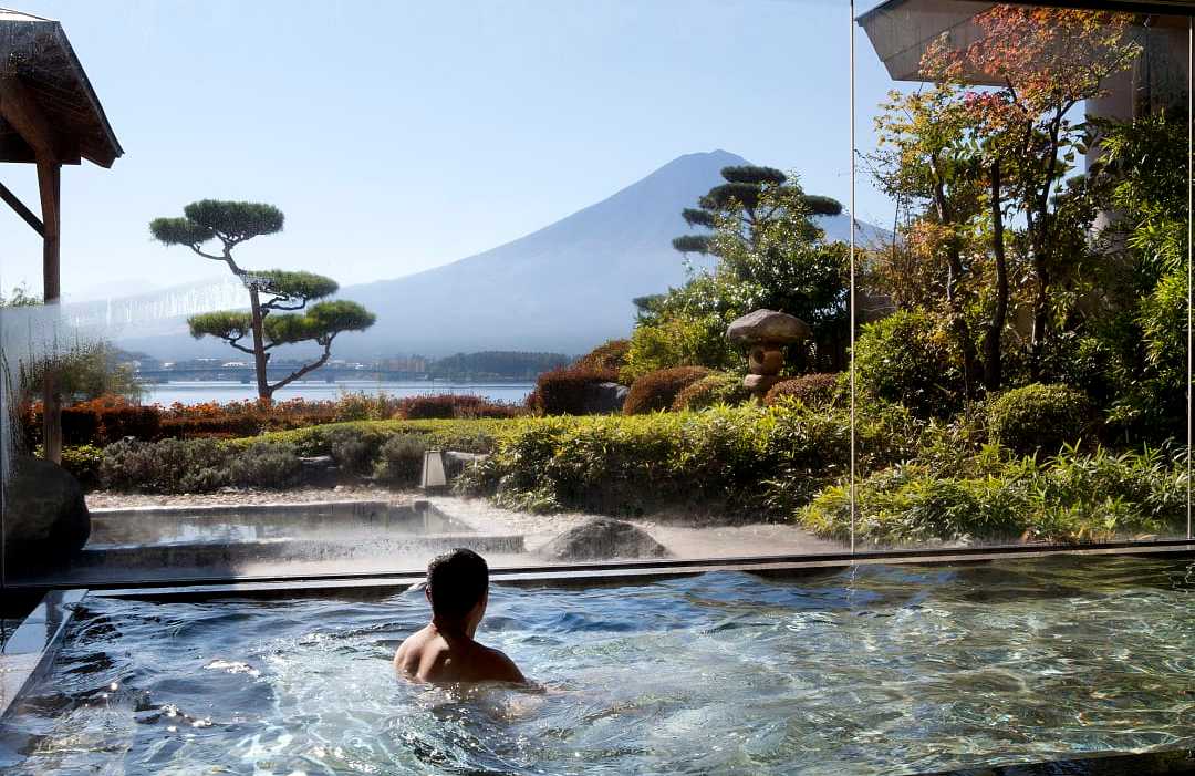 Man enjoying a luxury spa experience at Kawaguchi Lake and Mount Fuji in the background