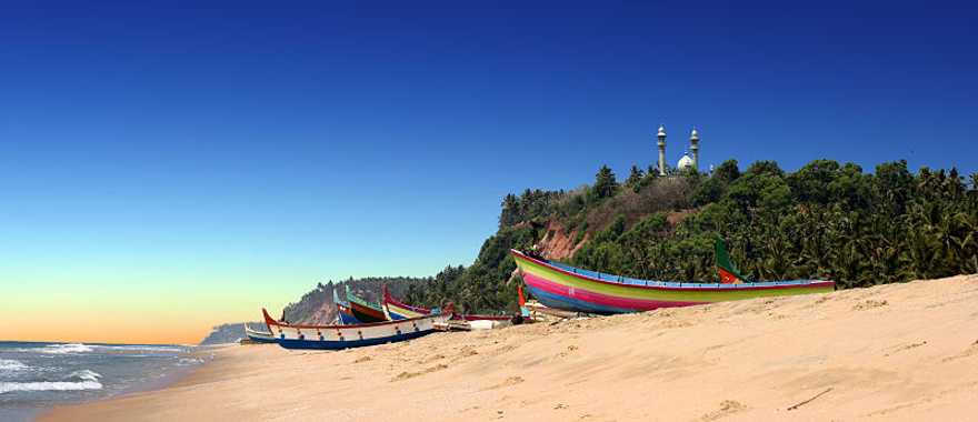 Colorful fishermen boats on beach in front of Varkala south cliff in Kerala, India
