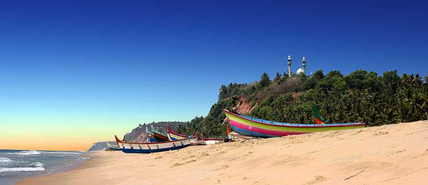 Colorful fishermen boats on beach in front of Varkala south cliff in Kerala, India
