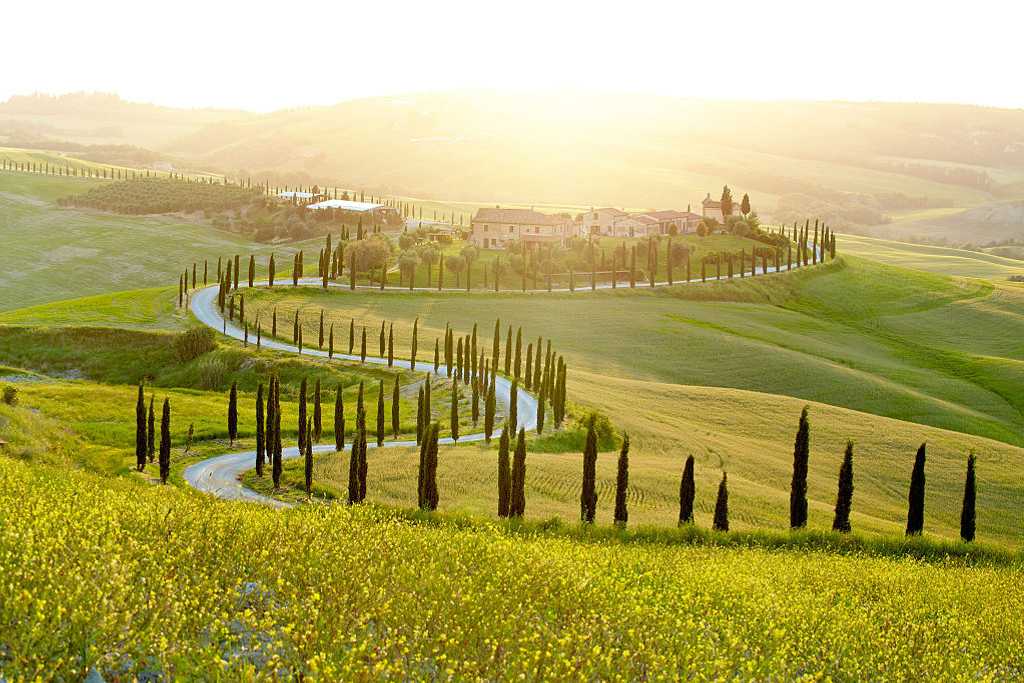 A farmhouse sitting in sunny fields in Tuscany.