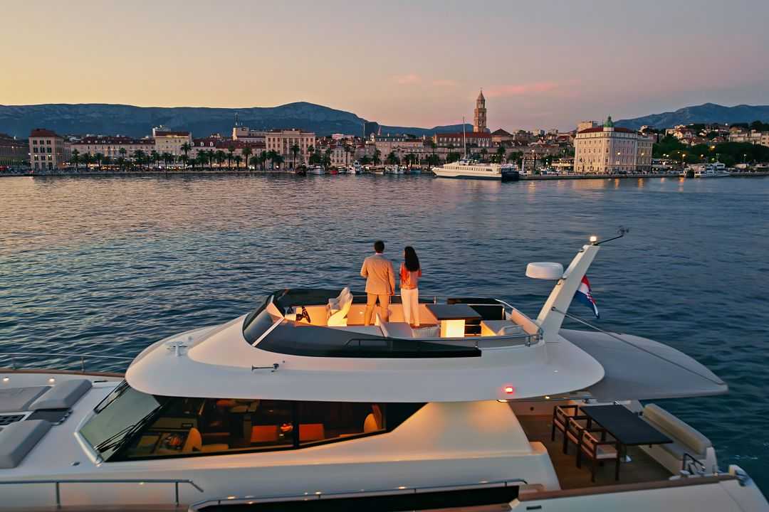 Couple on a luxury yacht admiring the Split skyline during dusk in Croatia