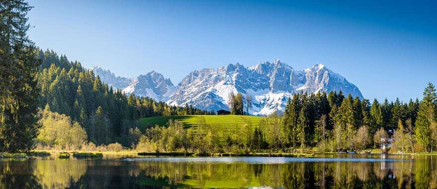 Idyllic alpine scenery, snowy mountains mirroring in a small lake in Tyrol, Austria.