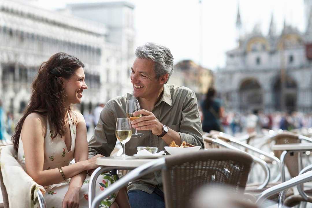 Couple drinking wine and dining al fresco in Venice, Italy