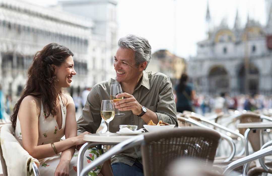 Couple drinking wine and dining al fresco in Venice, Italy