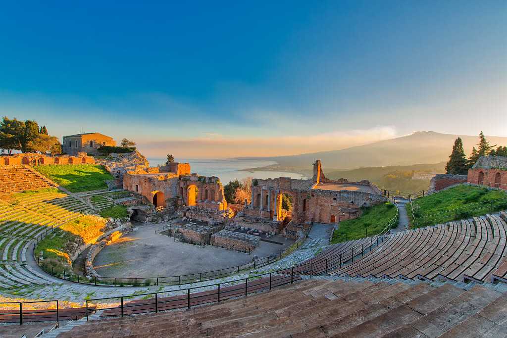 Ancient theatre of Taormina in Sicily with Mount Etna in the background at sunset