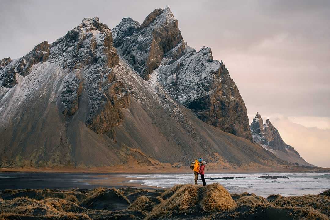 Tourist couple sharing a romantic moment on the black sand beach at Mount Vestrahorn