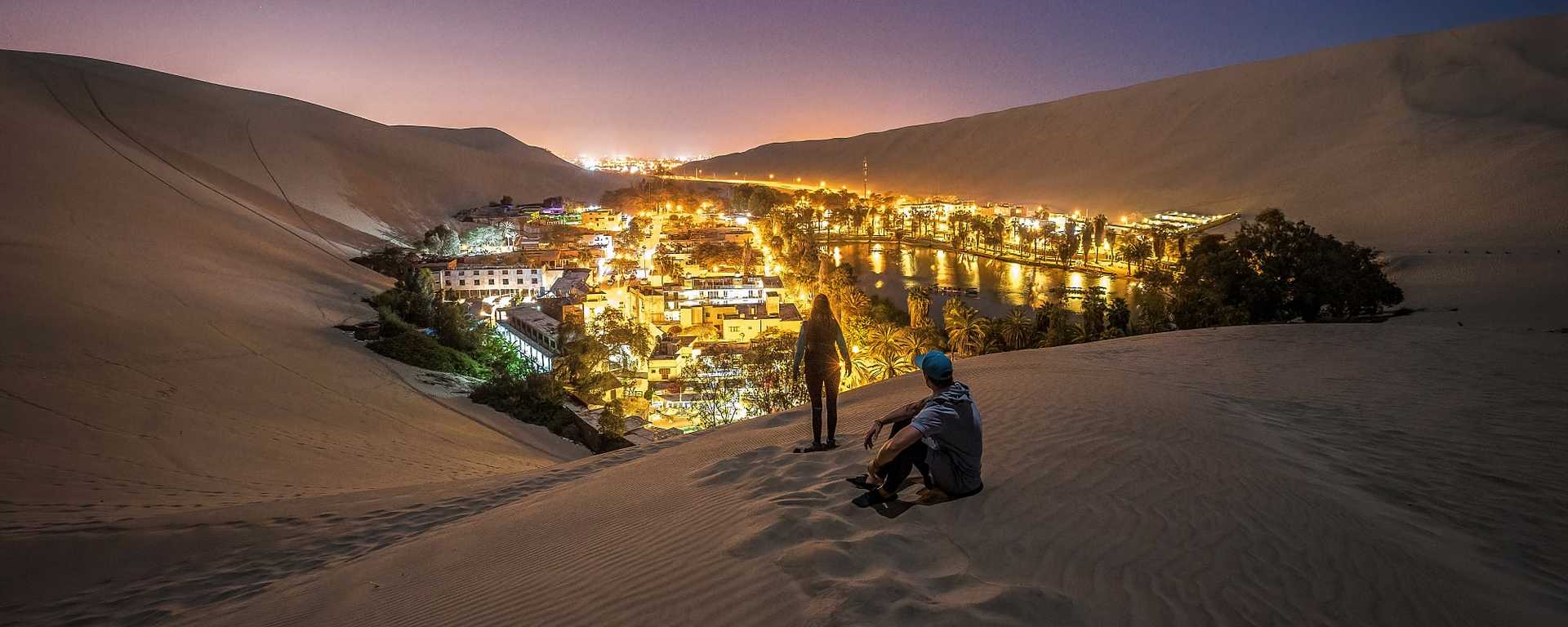 Couple on the dunes surrounding desert oasis Huacachina in southwestern Peru