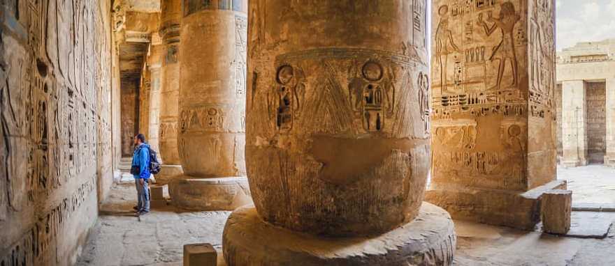 Traveler viewing hieroglyphs on the walls of the Temple of Medinet Habu in Egypt Traveler viewing hieroglyphs on the walls of the Temple of Medinet Habu in Egypt