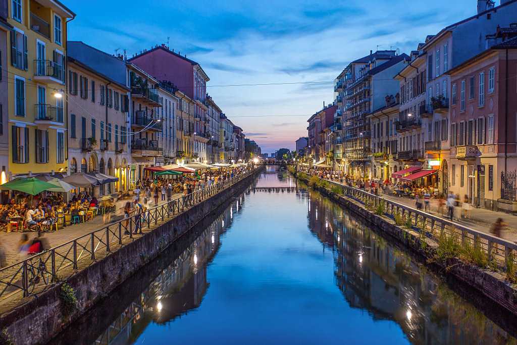 Restaurants lining Naviglio Grande Canal at dusk in Milan, Italy