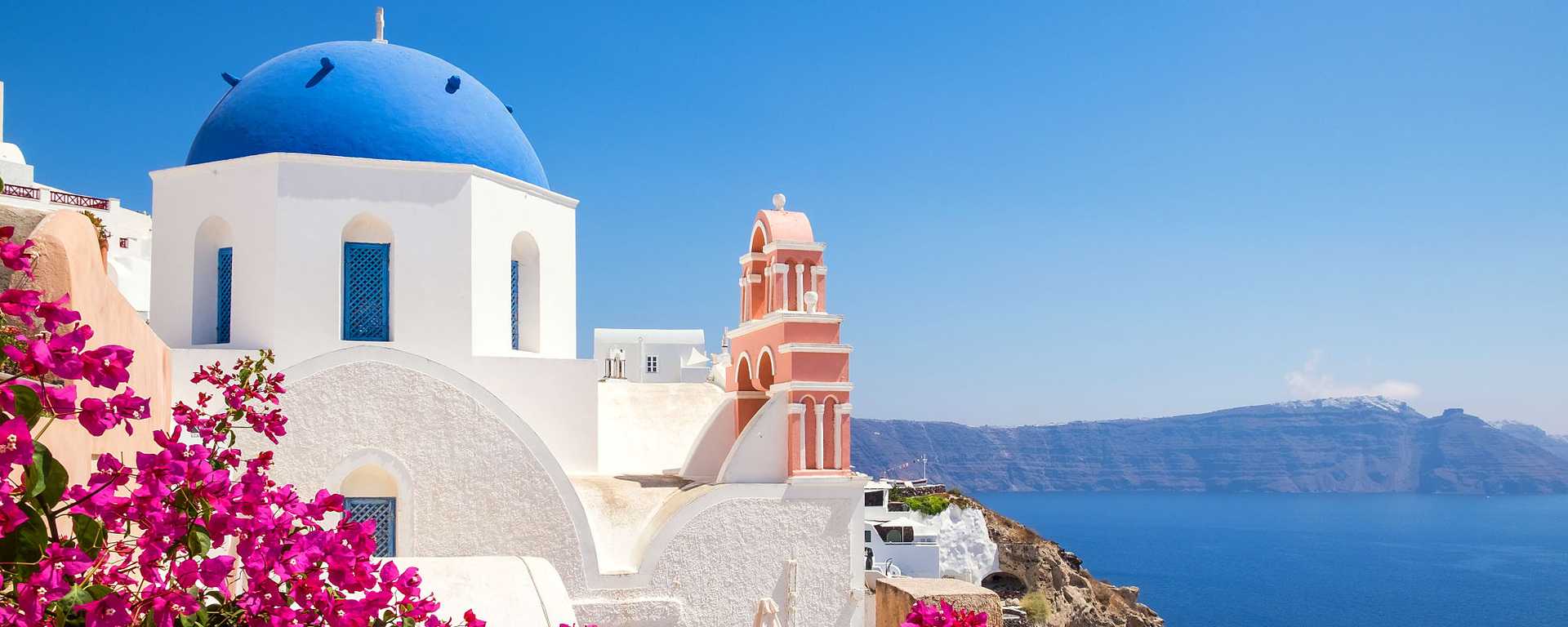 Scenic view of traditional cycladic house with flowers in the foreground at Oia village in Santorini, Greece.
