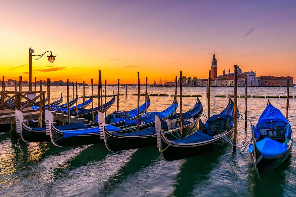 Gondolas moored at the pier on San Marco square during sunrise in Venice, Italy