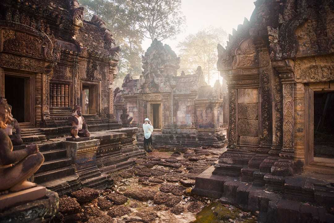 Woman photographing the serene majesty amongst the ruins of Angkor Wat in Siem Reap, Cambodia