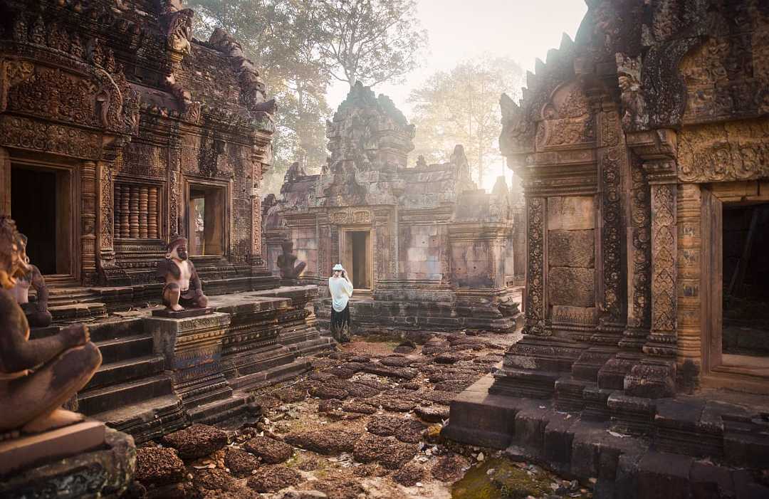 Woman photographing the serene majesty amongst the ruins of Angkor Wat in Siem Reap, Cambodia